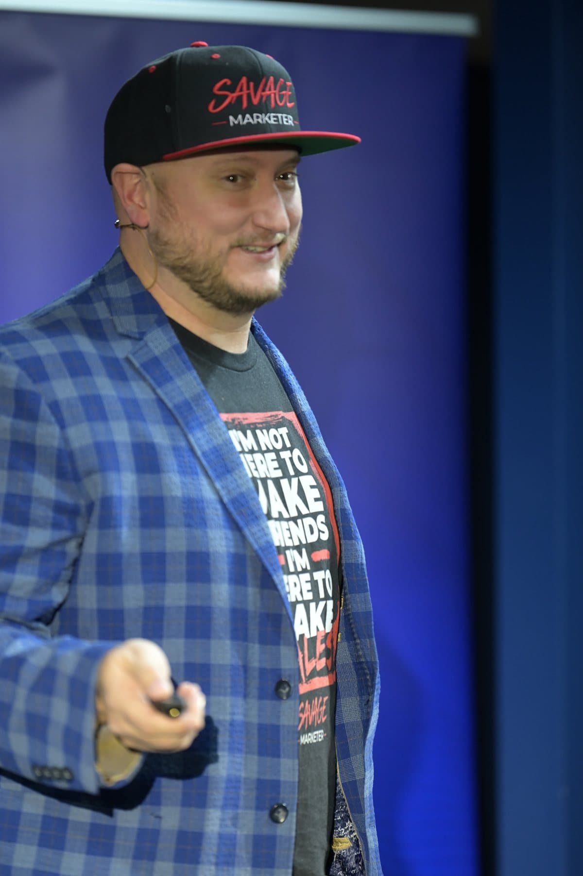 Jeff J Hunter speaking at a keynote (SAVAGE Marketer cap, blue blazer)
